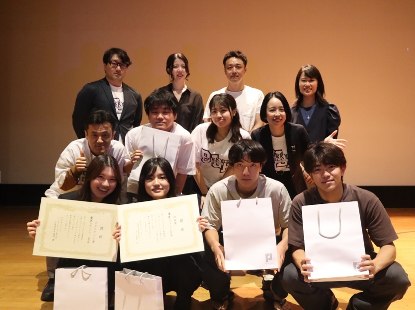 ステージでパーソルホールディングス社員と受賞した学生が集合し、表彰状や紙袋を手に持ちながら記念撮影をしている場面。